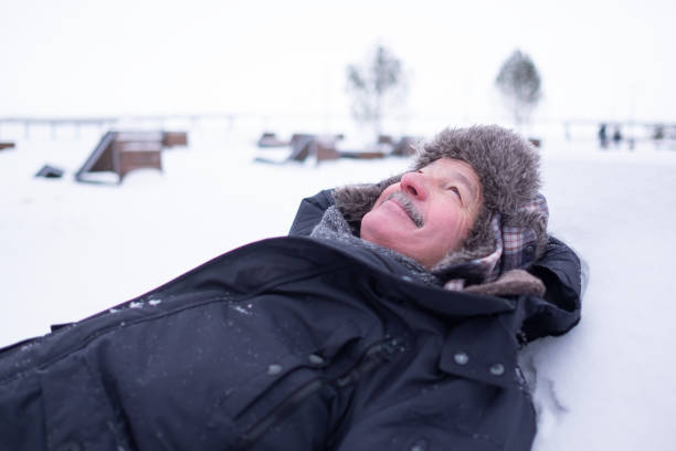 istock Senior handsome man in warm clothes and hat lying on snow and dreaming 1091709718
