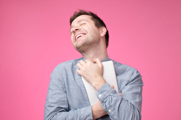 istock Happy young man holding tablet standing over pink wall 1091711074