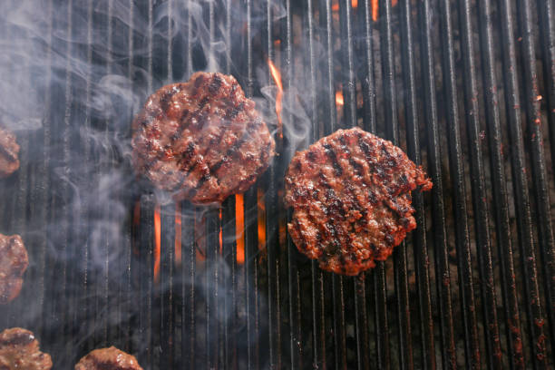 BBQ cooking cheeseburgers on a hot flaming grill stock photo