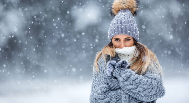 портрет молодой красивой женщины в зимней одежде и сильном снеге. - winter clothing hat human eye стоковые фото и изображения