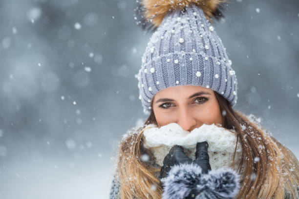 портрет молодой красивой женщины в зимней одежде и сильном снеге. - winter clothing hat human eye стоковые фото и изображения