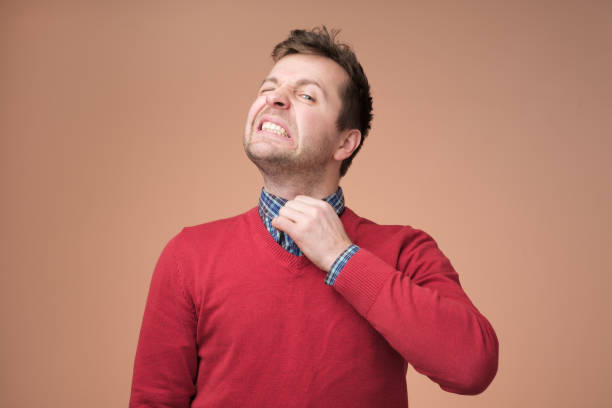 Young europeam man in red sweater feeeling uncomfortable. Young europeam man in red sweater feeeling uncomfortable. Colar is tight and stuffy and he tries to expand the collar to make a breath. Hate office clothes uncomfortable stock pictures, royalty-free photos & images