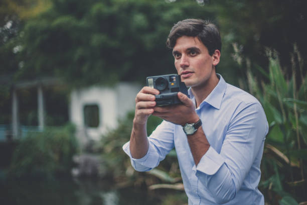 istock Man takes photo with poraroid camera 1091713340