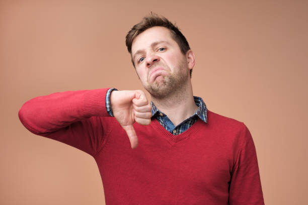 istock Young man in red sweater showing thumbs down 1091713412