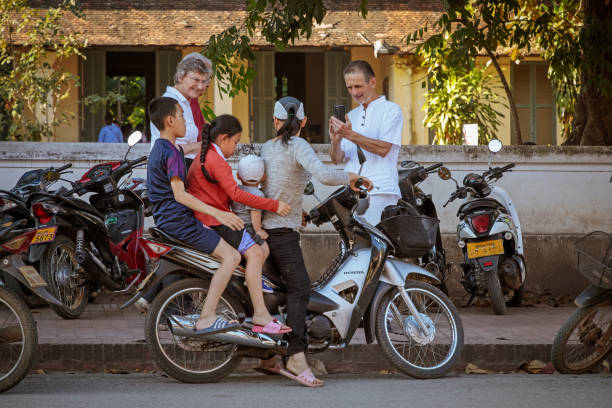 Luang Prabang, Laos - December 6, 2018: Four young people preparing to go home from school on a motorcycle in Luang Prabang, the former capital of Laos
