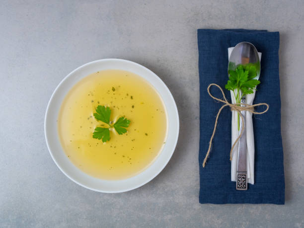 Clear soup with fresh parsley Eating utensils, spoon, water glass, herbs, diet, weight loss, alkaline fasting, fasting cure, table, vegetable broth fasting stock pictures, royalty-free photos & images