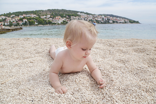 Adorable cheerful baby crawling on the pebble beach