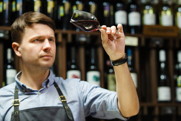 Bokal of red wine on background, male sommelier appreciating drink Bokal of red wine on background of male sommelier appreciating color, quality, flavor and sediments of drink. Professional degustation expert in winemaking. sommelier photos stock pictures, royalty-free photos & images
