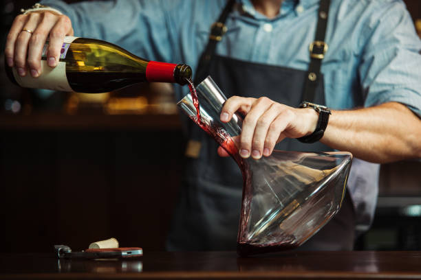 sommelier gießt rotwein in dekanter, um perfekte farbe zu machen - decanter wine wineglass red wine stock-fotos und bilder