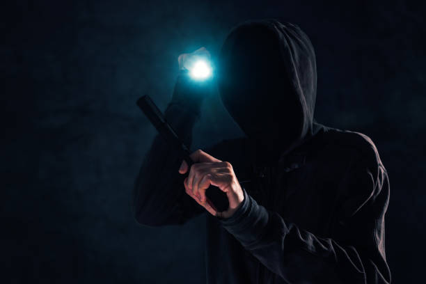 istock Armed robbery, criminal with hoodie holding gun and torchlight 1091728176