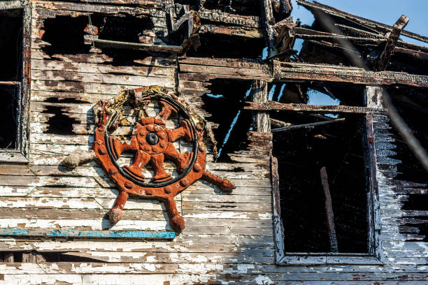 o deck esquerdo de um velho barco de madeira que sofreu um incêndio contra o leme do navio. - burnt furniture chair old - fotografias e filmes do acervo