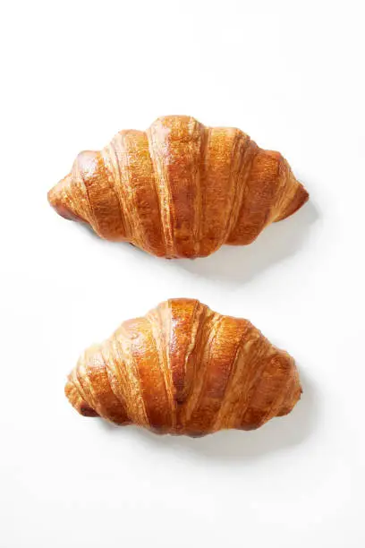 Photo of Two croissants isolated on a white background viewed from above. Top view.