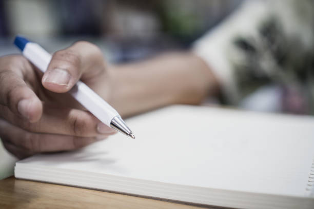 istock Man student taking and writing notes on notebook with pen in library at college university for homework. Education learning studying in school concept 1091737266