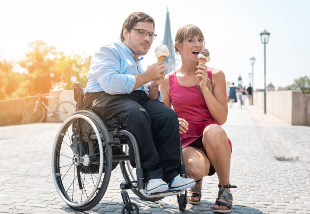 Disabled man and his friend having ice cream in town during a city excursion