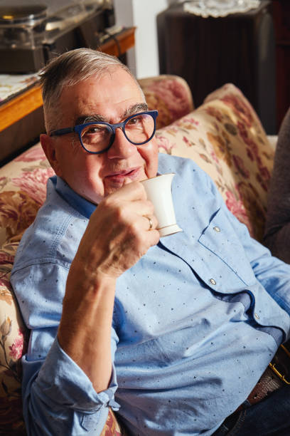 istock happy elderly man sitting on the sofa and enjoys coffee. 1091746518