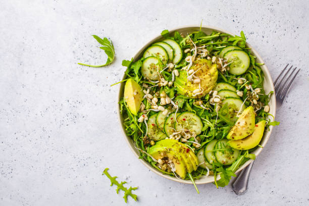 Healthy green salad with avocado, cucumber and arugula in white dish, top view, copy space. Healthy green salad with avocado, cucumber and arugula in white dish. Plant based diet concept. spring mix lettuce leaves stock pictures, royalty-free photos & images