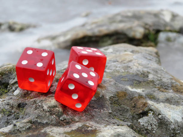 Red dice with water drops on the rocks in the seacoast