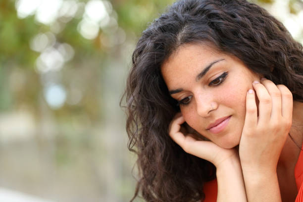 istock Pensive melancholic woman looking down in a park 1091755174