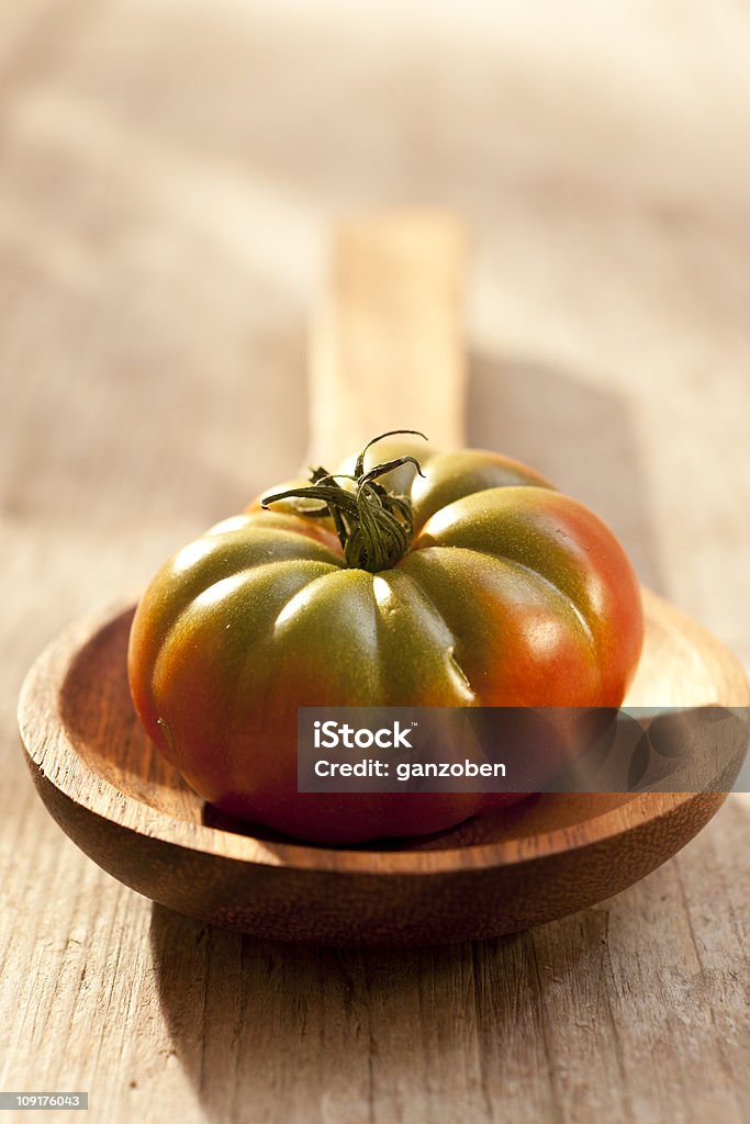 Tomate en una cuchara de madera - Foto de stock de Tomate Heirloom libre de derechos