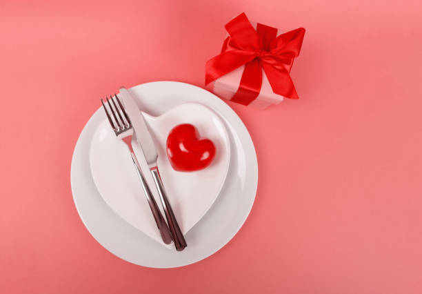 istock Red heart on white plate with kitchen cutlery on living coral table 1091763534