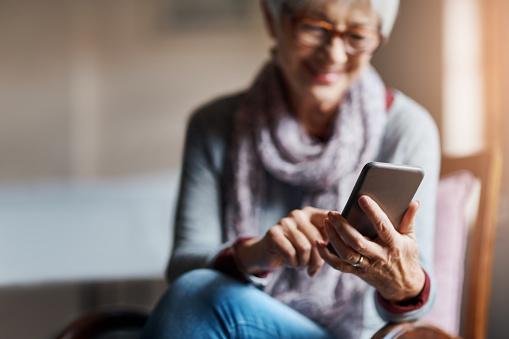 Shot of a senior woman using a mobile phone in a retirement home