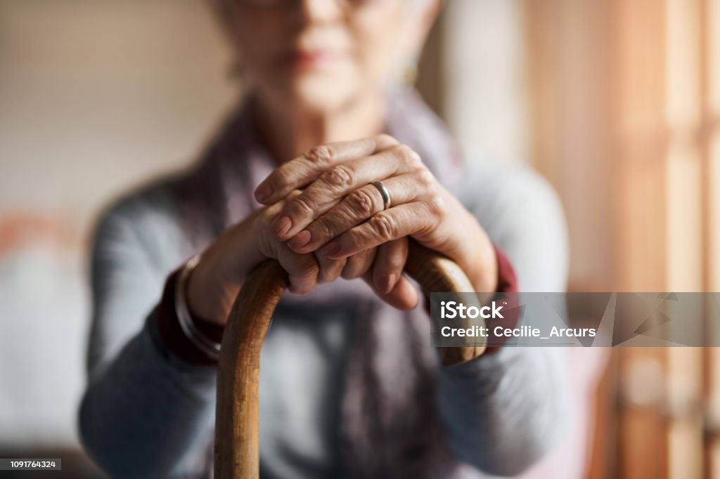 I get by with a little help from my cane Cropped shot of a senior woman holding a cane in a retirement home Senior Adult Stock Photo