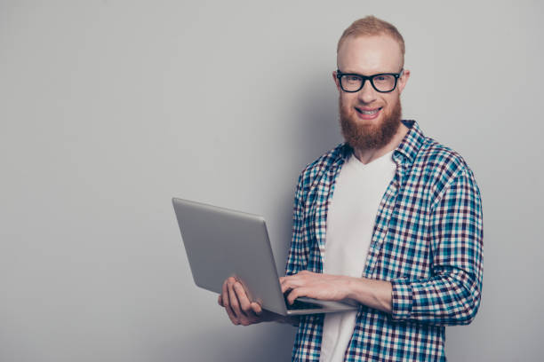 istock Portrait of nice cool man look at camera stand isolated on light gray background using netbook make beaming white hollywood smile 1091766214