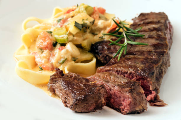 istock Grilled rump steak with vegetable sauce and pasta on a light gray background 1091769360