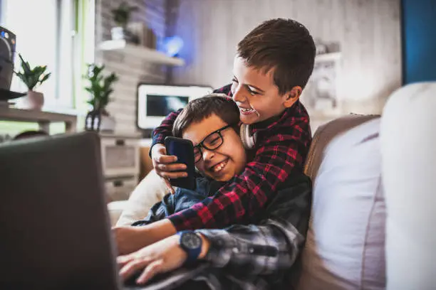Photo of Two teenage boys with gadgets on couch at home