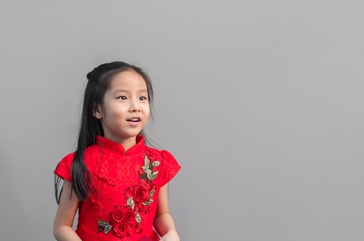 Cute Asian girl in chinese cheongsam and Tradition Chinese dress with red envelope , Chinese new year concept , grey background