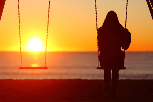 mujer sentada en un columpio contemplando la puesta de sol - lost beach fotografías e imágenes de stock