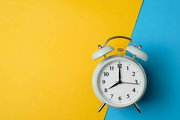istock vintage alarm clock on two tone solid color yellow and light blue background 1091788264