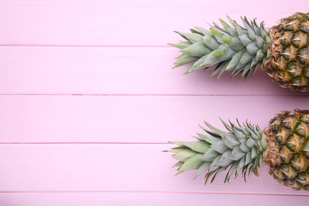 istock Two ripe pineapples on a pink wooden background 1091804424