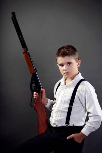 Well dressed young man. An 8 year old boy dressed in a tuxedo poses with his pellet gun. dinner jacket stock pictures, royalty-free photos & images