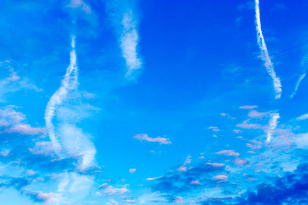 istock Pattern of blue, pink and white clouds, airplane trails on blue sky 1091838578