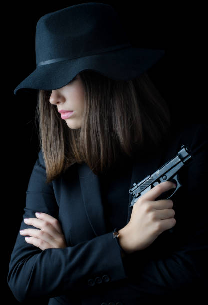 istock Young woman in black holding gun 1091840442