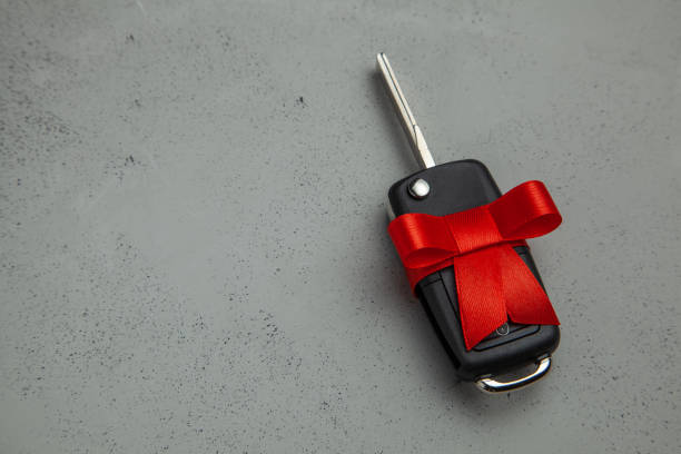 istock Gift Car keys with remote control alarm with red ribbon with bow. Gray background. Copy space for text. 1091852048