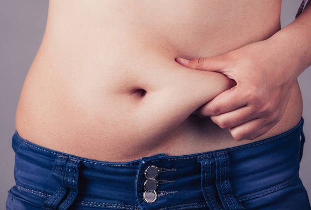 Woman squeezing fat belly Woman squeezing belly fat around belly button pot belly stock pictures, royalty-free photos & images