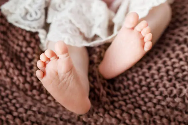 Photo of Newborn baby feet on knitted plaid. Closeup picture. Tiny newborn baby's feet  closeup.