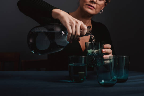 istock Woman pouring serving water dark low key table setting in blue 1091869504