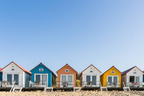 Colored beach houses in a row Along the beach of The Netherlands you can find lots of colored beach houses. They are occupied by tourists who stay there for the weekend or spen their holiday there beach hut stock pictures, royalty-free photos & images