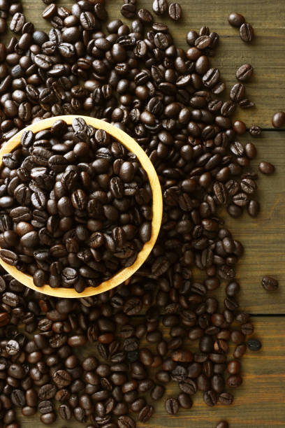 Coffee beans in the bowl on wooden background.