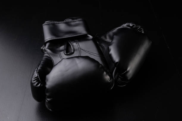 istock Black boxing gloves on the gym table. Training accessories. Dark background. 1091884744