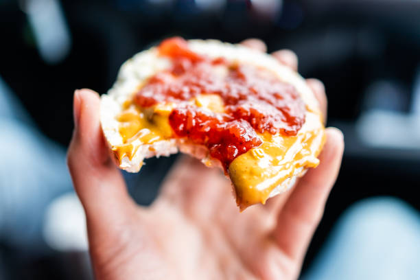 makro nahaufnahme von hand mit einem reiskuchen in auto straße reise unscharfen hintergrund garniert mit erdnussbutter, erdbeermarmelade, vegan dessert snack - strawberry fruit single object food stock-fotos und bilder