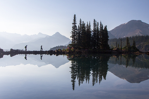 Hikers reflect in the water at Garibaldi Lake in British Columbia.