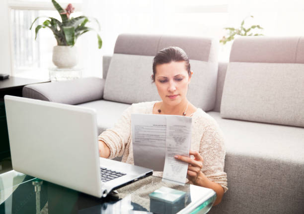 Woman Filing Income Tax Online Woman in her 30s filling out tax information online filing paperwork stock pictures, royalty-free photos & images