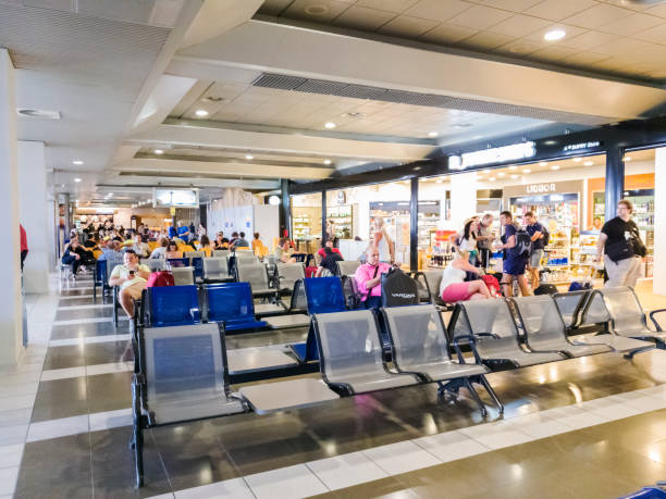 Unidentified people waiting at boarding area next to the departure gates & expanded & renovated area of Hellenic Duty Free Shops. Thessaloniki, Greece - July 16 2018: SKG airport gates with passengers waiting to board their flight. skg stock pictures, royalty-free photos & images