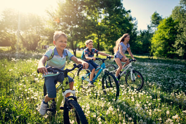 enfants cheval bicyclettes au champ pissenlit - cycling bicycle healthy lifestyle green photos et images de collection