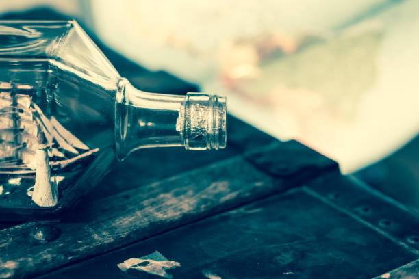 a vintage whiskey bottle containing a ship and light house, resting on a trunk - trunk luggage old fashioned retro revival imagens e fotografias de stock