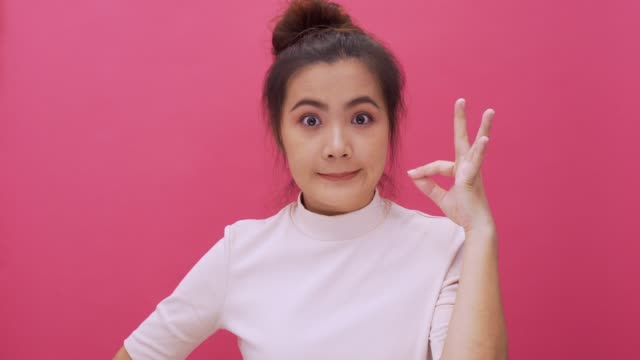 Woman making shush gesture on isolated pink background 4k